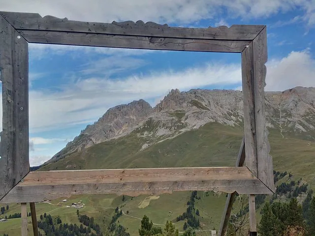 Large wooden picture frame framing a view of rugged mountain peaks.