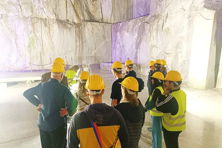 Gruppo di turisti con caschi di protezione in una grande caverna di marmo.