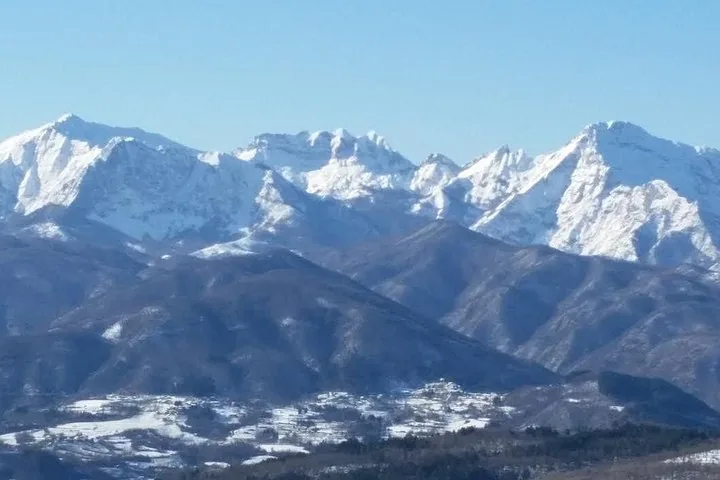 Vette innevate che si ergono sopra una valle con case sparse.