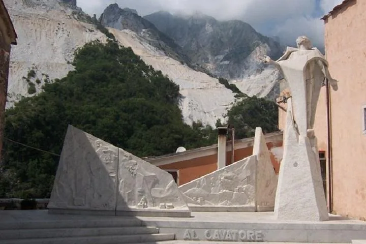 Marble statues and monuments with the quarry mountains in the background.